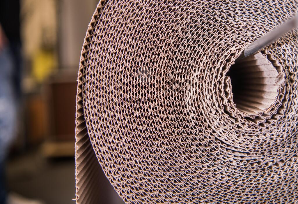 Brown roll of corrugated packaging carton material used for wrapping, protecting, and packing household items during storage, shipping, and relocation.